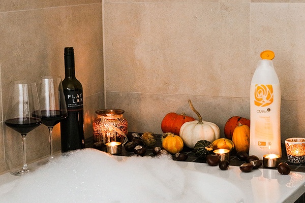 Eine Badewanne mit Schaum und herbstlicher Dekoration wie Wein und Kürbisse