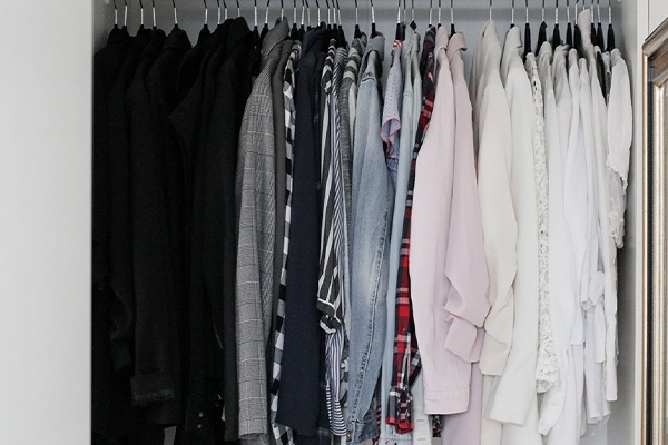 Kleider im Schrank hängend nach Farben sortiert 