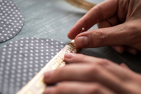 Ein Geschenkband wird auf ein rundes Stück Stoff genäht.