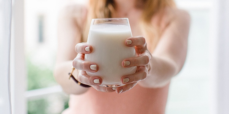 Ein großes Glas Milch in der Hand  