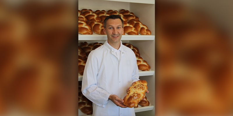 Bäcker hält einen Strizel in der Hand