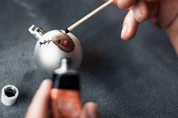 Eine Chrisbaumkugel wird mit einem Rentier bemalt.