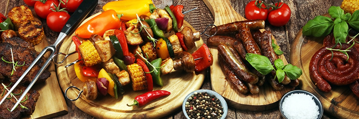 Gegrilltes Gemüse und Fleisch auf Holzbrettern