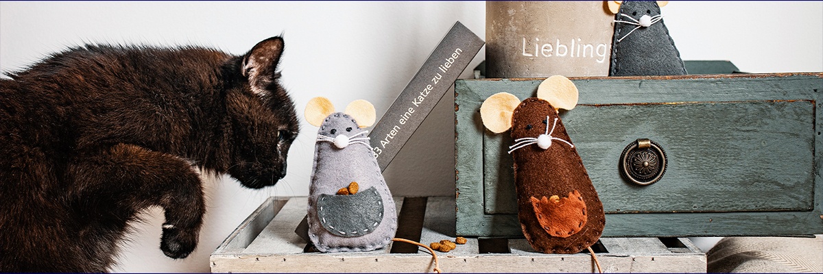 Schwarze Katze mit zwei Filz-Spielmäusen