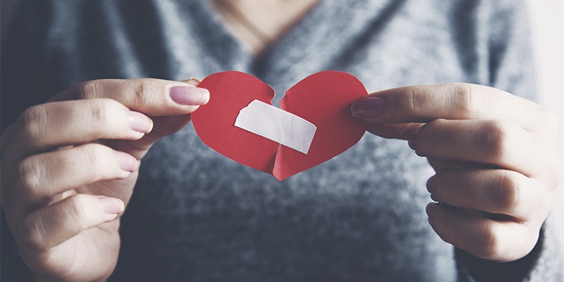 Ein zerrissenes Herz wird mit Klebeband zusammengefügt.