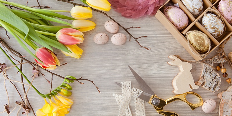 Tulpen,  zwei Holzhasen und Deko-Eier auf Holzuntergrund