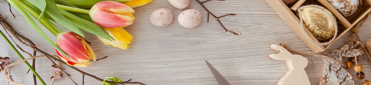 Tulpen mit roten Blüten und grünen Stängeln und Holzhase auf Holztisch