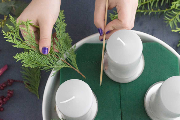 Kerzen auf Steckschaum mit Ästen dekoriert