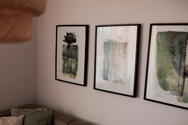 Drei Bilder in Grüntönen auf einer Wand.