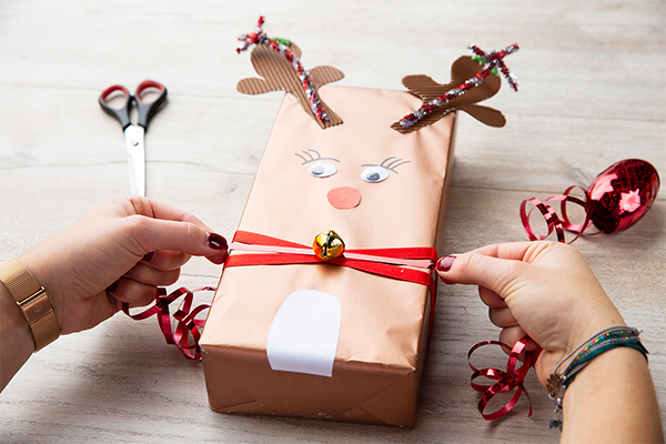 Geschenk als Rentier dekoriert mit Glöckchen und einem roten Band