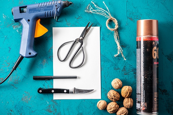 Utensilien für selbstgemachte Glücksnüsse, wie Sprayfarbe, Messer, Tonpapier und Heißkleber