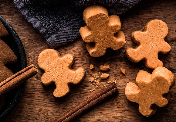 Badebomben in Lebkuchen-Form neben Zimtstangen 