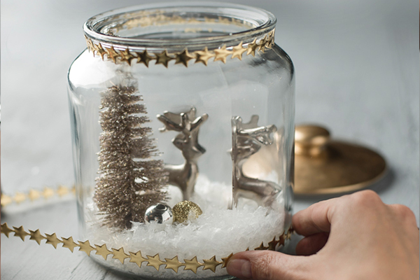 Glas mit goldenen Rentieren, Baum und Kunstschnee