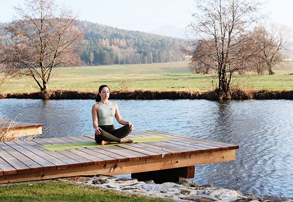 Natacha von The Chocolate Suitcase beim Meditieren auf einem Steg am See 