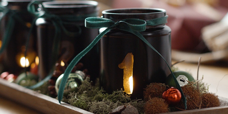 Leuchtender Upcycling-Adventkranz dekoriert auf einer Holzplatte 