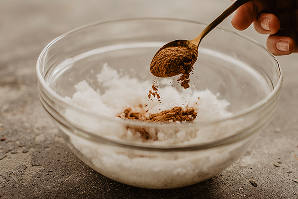 Zimt wird mit einem Löffel in eine Schüssel gegeben