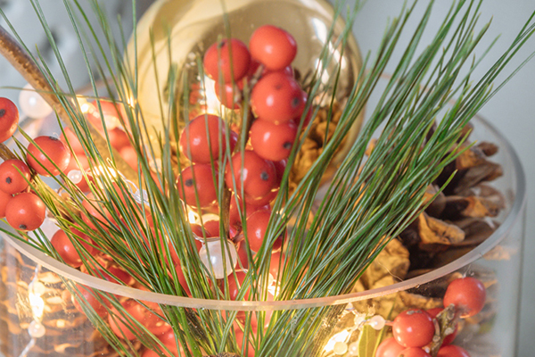 Weihnachtliches Gesteck im Glas mit einer Lichterkette