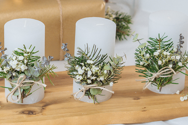 Drei Kerzen mit grünen Ästen verziert