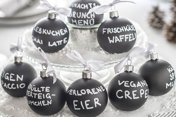 Schwarze Christbaumkugeln mit weißer Aufschrift von Gerichten