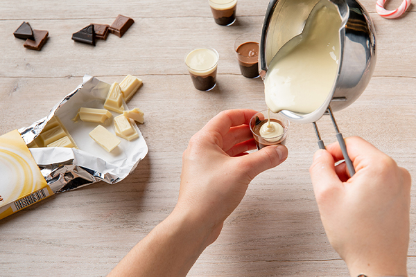 Schokolade wird in ein Plastik-Schnapsglas gegossen