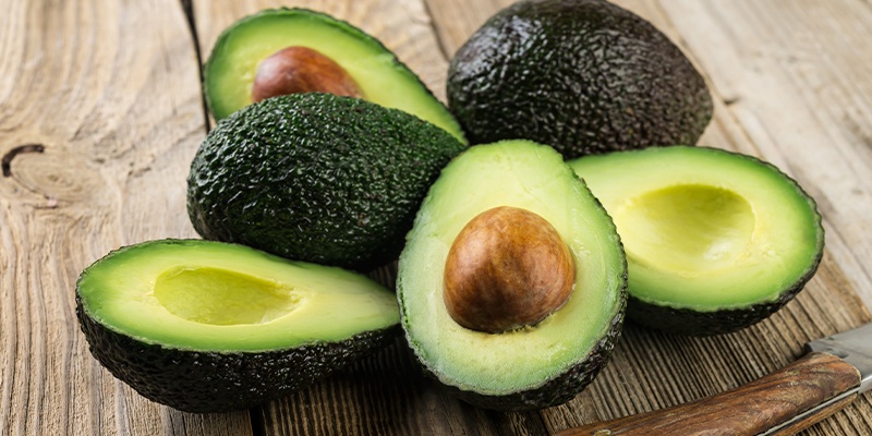 Ganze und halbe Avocado auf braunen Tisch