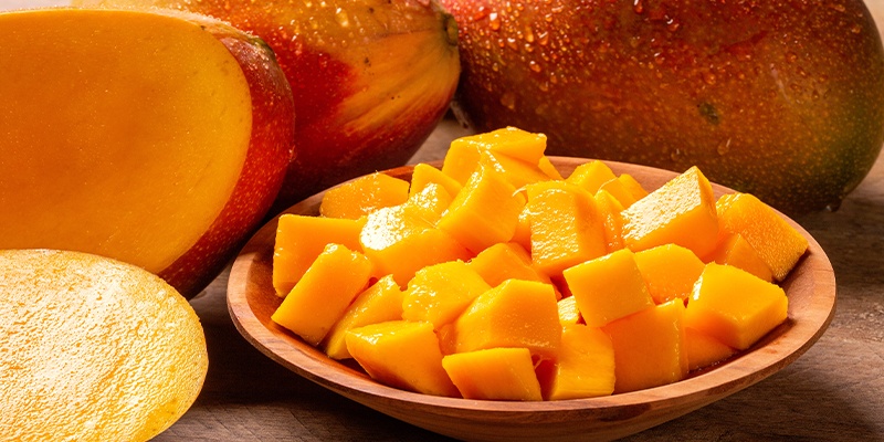 Reife orange Mango in einer Terrakottaschüssel auf braunen Tisch