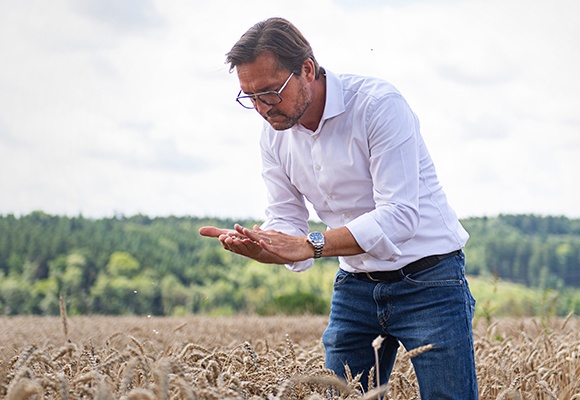 Ein Mann mit weißem Hemd und dunklem Sako steht vor einer Produktionsmaschine.