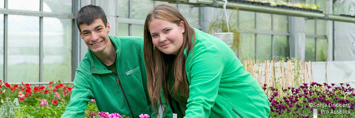 Eine Frau und ein Mann in einem großen Glashaus für Blumen