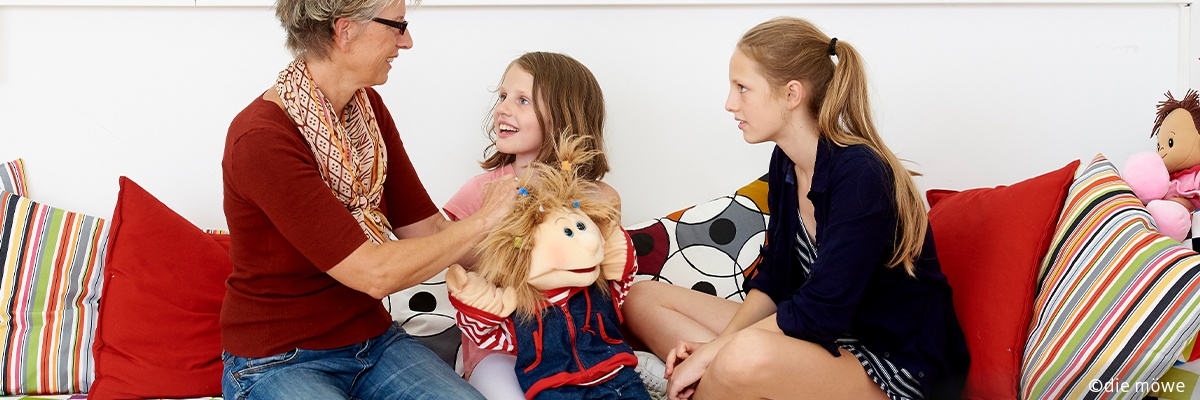 Frau sitzt mit zwei Kindern auf einem Sofa.