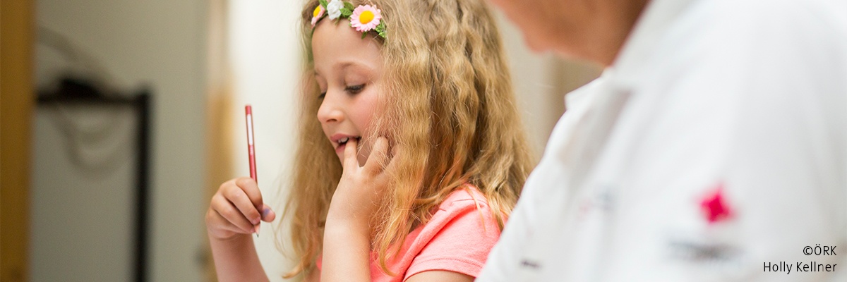 Eine Frau vom roten Kreuz hilft einem Mädchen bei der Hausübung