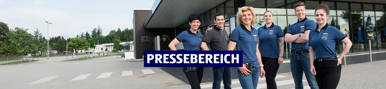 Sechs Mitarbeiterinnen und Mitarbeiter vor einer HOFER Filiale