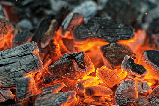 Auf dem Bild sind glühende Holzkohle Briketts zu sehen.
