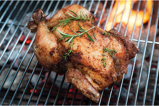 Auf dem Bild ist ein Geflügel auf einem Grillrost ersichtlich. Das Geflügel ist mariniert und mit Rosmarin garniert.