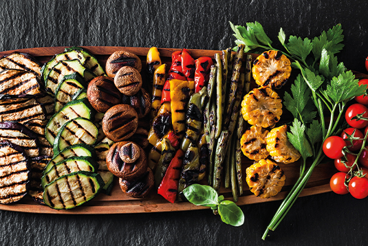 Auf dem Bild sind gegrillte Auberginen, Zucchini, Champignons, Paprika, Bohnen sowie Mais ersichtlich.