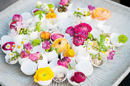 Weiße Ostereierschalen sind mit bunten Blumen gefüllt.