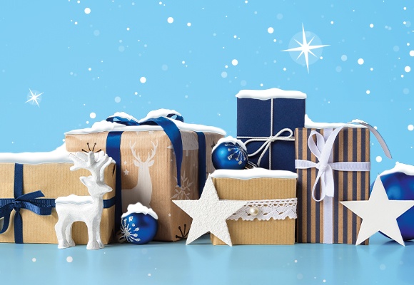 Geschenke und Deko auf blauem Hintergrund mit Schneeflocken und Sternen, festliche Winterstimmung.