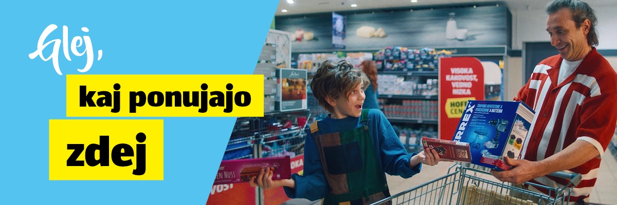 Napis: Glej kaj ponujajo zdej, v ozadju deček in moški v trgovini