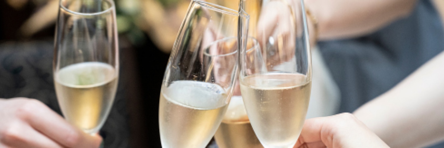 3 Gläser Sekt auf einem Holztisch mit Weintrauben als Dekoration, Weinberg im Hintergrund