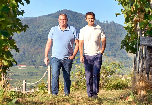 Zwei Männer spazieren über ein Weingut