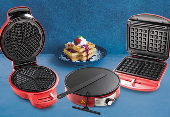 Pekači za palačinke in vaflje, rdeče barve, v ozadju pečeni vaflji