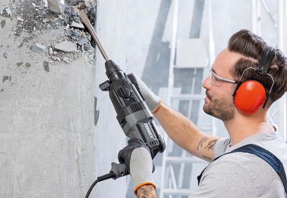 Moški drži v roki udarno kladivo