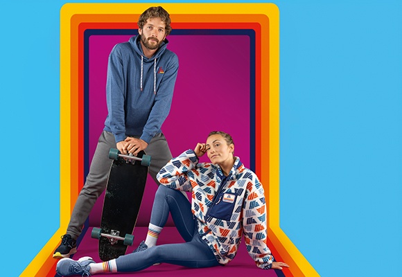 Moški se opira na rolko, ženska sedi na tleh, oblečena sta v oblačila znamke Hofer