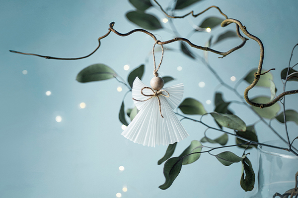 Weihnachtsengel auf einem Ast, hellblauer Hintergrund