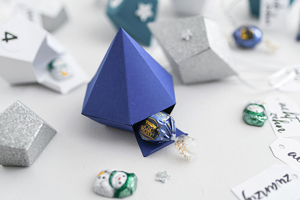 Auf dem Bild sind Diamanten aus Papier in blau und silber ersichtlich. Diese sind mit MOSER ROTH Süßwaren gefüllt.