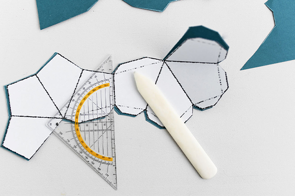 Auf dem Bild ist ein Geodreieck mit einem Stift und einer Druckvorlage ersichtlich.