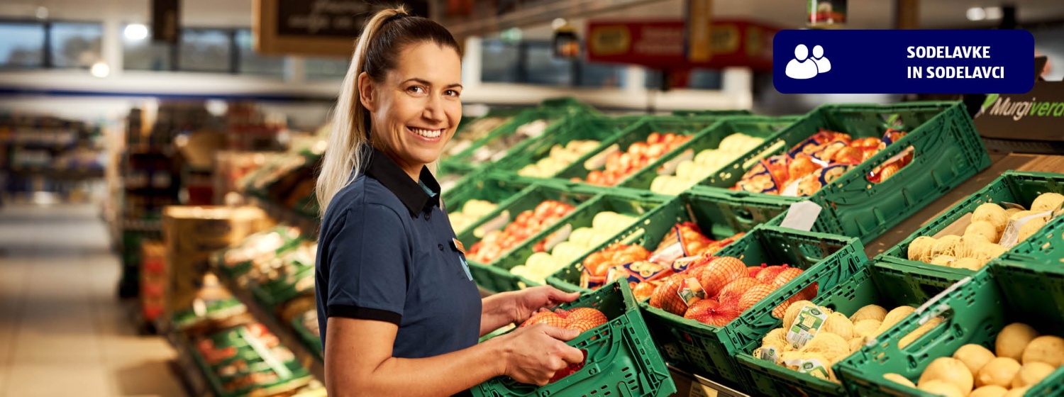 Nasmejana HOFERjeva prodajalka v trgovini nalaga sadje in zelenjavo