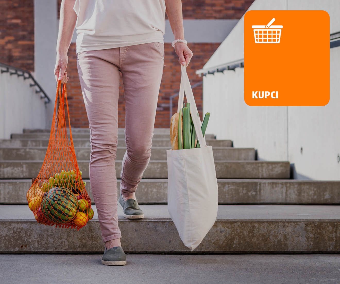 Ženska z dvema nakupovalnima vrečama v rokah, hodi po stopnicah