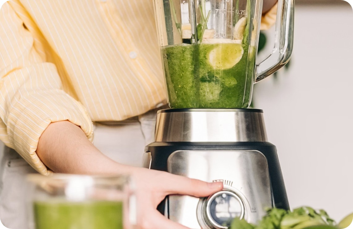 Eine Frau mixt einen grünen Saft mit Limette und Spinat