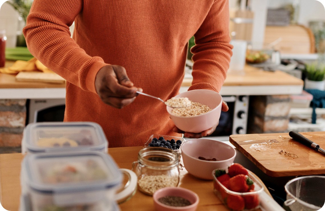 Eine Person bereitet ein Müsli aus Haferflocken und frischen Beeren zu.