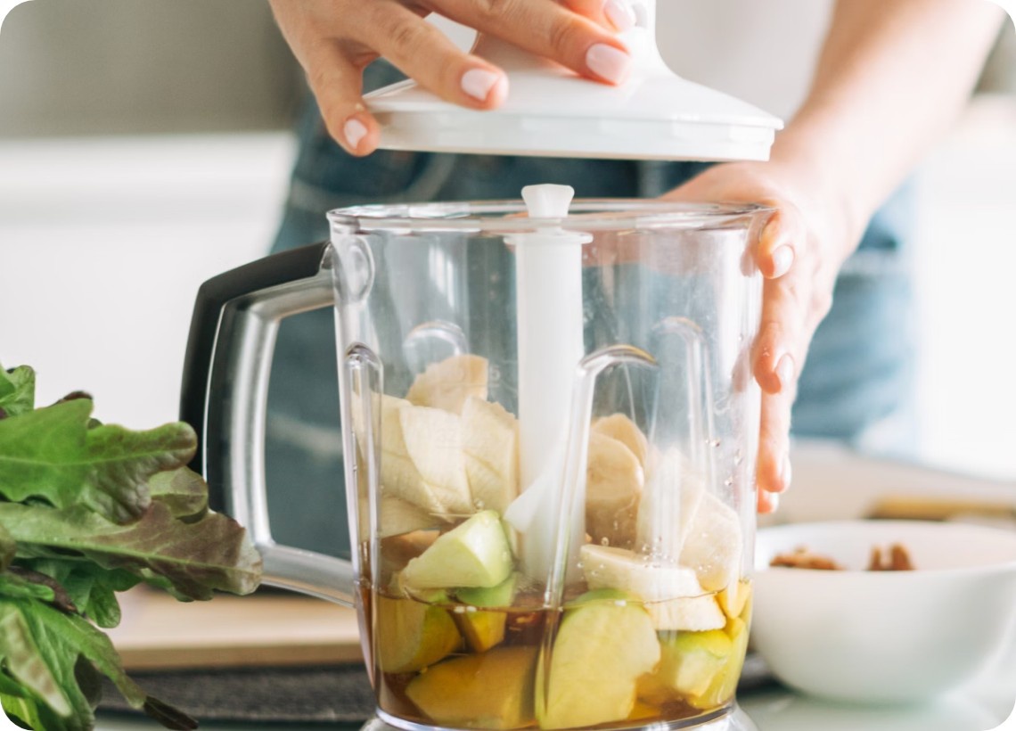 Eine Person bereitet sich einen Saft mit Obst zu.